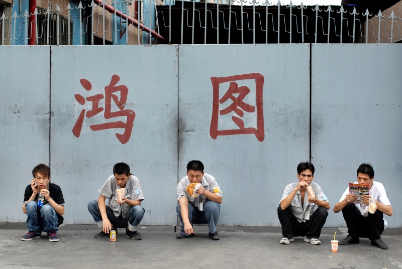 2011年9月4日,广东东莞,一家铸造厂的工人下班后,在厂门前边吃东西边放风。这只是暂时充饥,等到晚上10点钟加完班后,他们回到出租屋再自己做晚饭。