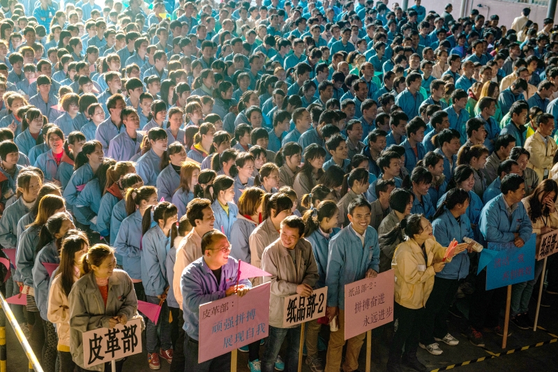 2015年12月31日, 广东东莞,某纸品厂的员工参加运动会,数万人站在空地上,肩连着肩、脚挨着脚,横是一条线,竖是一列队,老板站在台上,用大喇叭点评全厂工作。